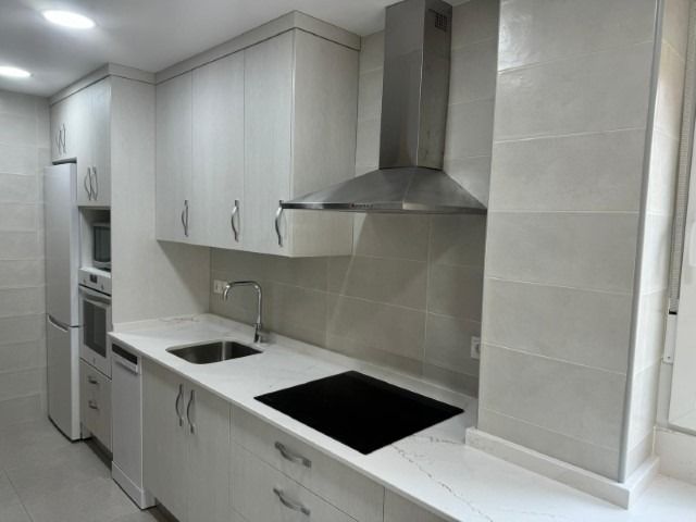Una cocina con gabinetes blancos y un horno de estufa.