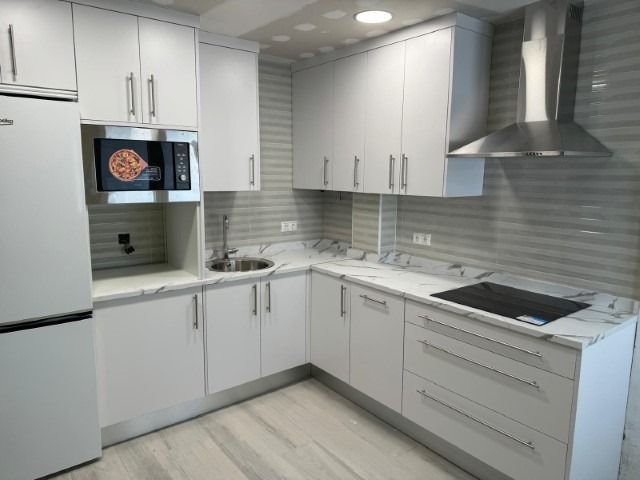 Una cocina con gabinetes blancos y un horno de estufa.