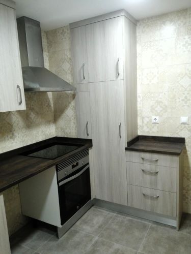 Una cocina con gabinetes de madera, una estufa y una campana extractora.