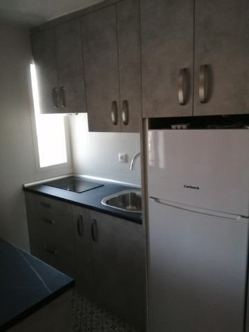 Una cocina con fregadero, refrigerador y armarios.