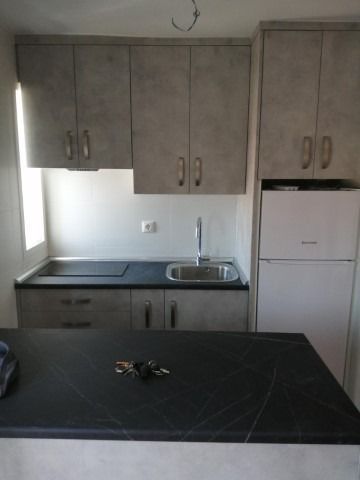 Una cocina con fregadero, refrigerador y armarios.