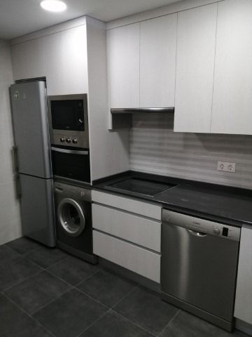 Una cocina con gabinetes blancos y electrodomésticos de acero inoxidable.