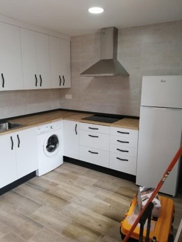 Una cocina con gabinetes blancos y un refrigerador.