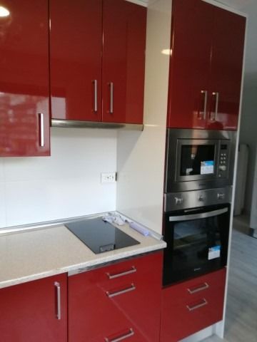 Una cocina con gabinetes rojos y un horno de estufa.