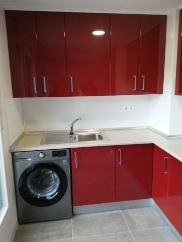 Una cocina con armarios rojos y lavadora.