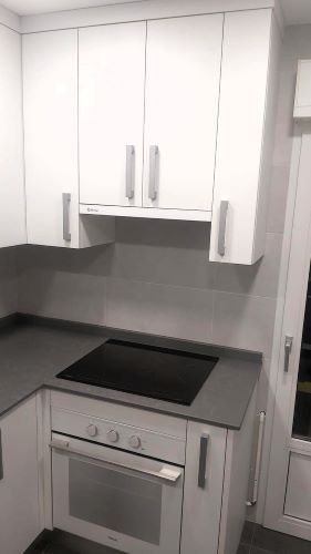 Una cocina con gabinetes blancos y un horno negro.