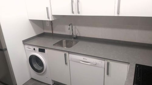 Una cocina con lavadora, fregadero y lavavajillas.