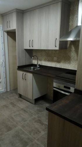 Una cocina con gabinetes blancos, un fregadero y una estufa.