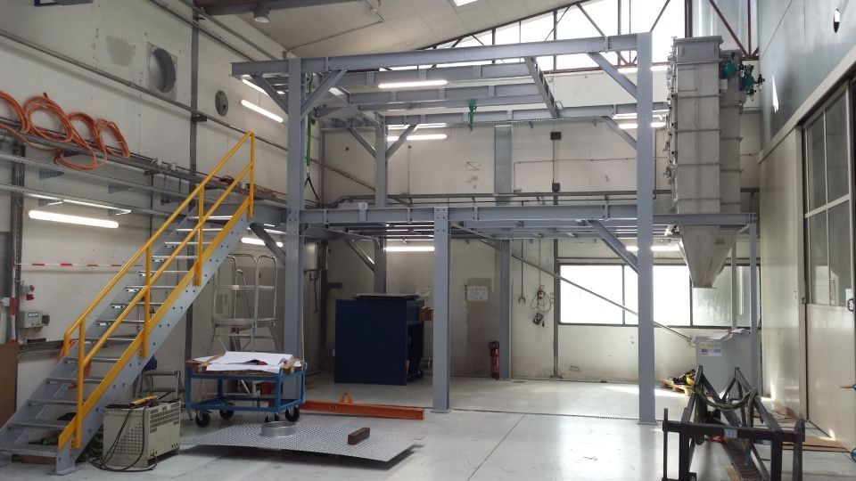 Structure industrielle en métal à l'intérieur d'une pièce lumineuse, avec escaliers, plates-formes et machines attachées.