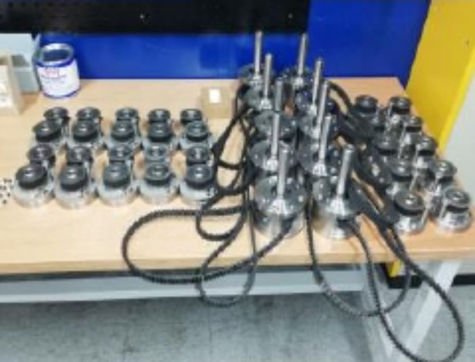 De nombreuses pièces de machines métalliques avec câbles sont posées sur une table en bois. 