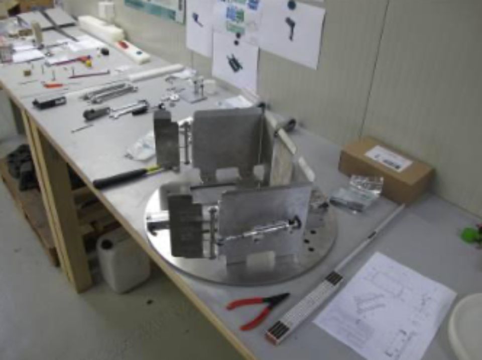 Table de travail avec outils et composants métalliques ; espace de travail potentiel d'ingénierie ou d'assemblage.