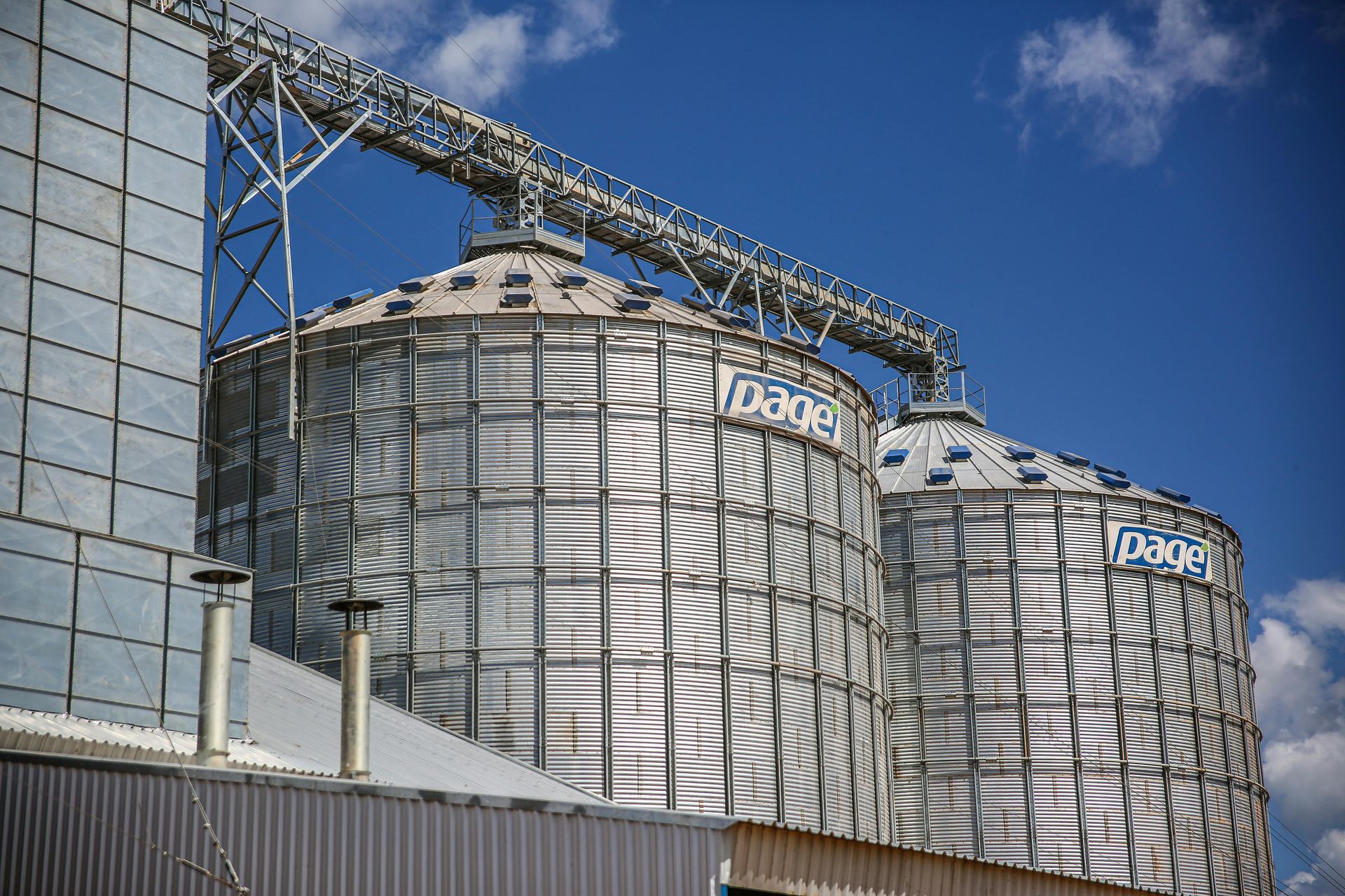 Dépoussiéreur industriel argenté sur une plateforme métallique, avec tuyauterie et une plateforme jaune au-dessus.