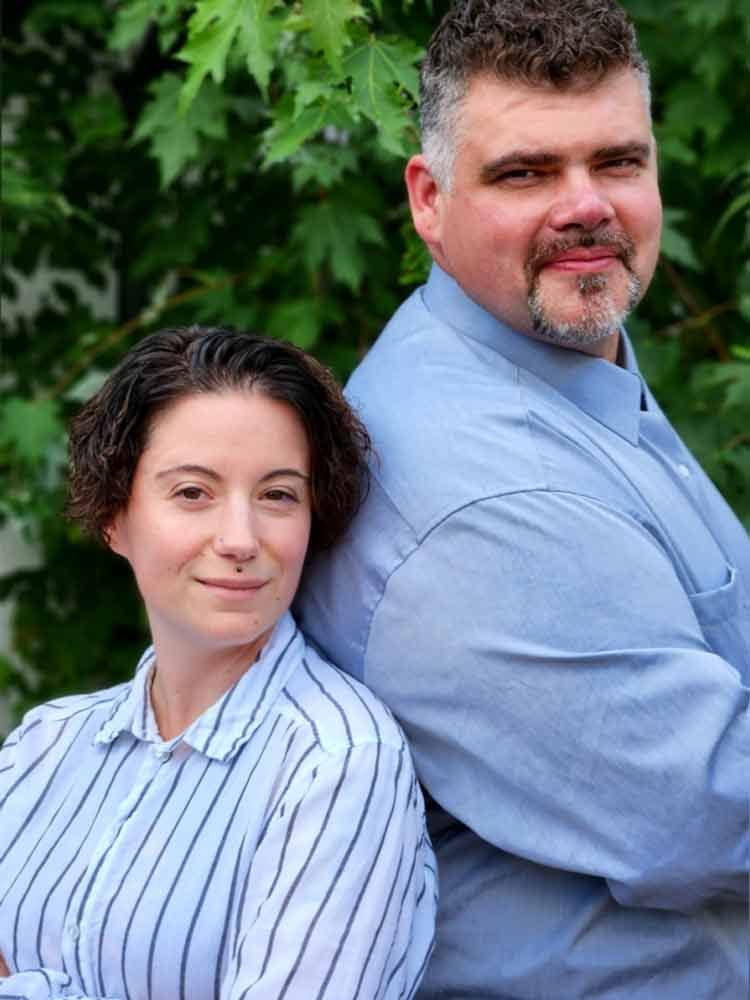 Ein Mann und eine Frau stehen Rücken an Rücken mit verschränkten Armen.