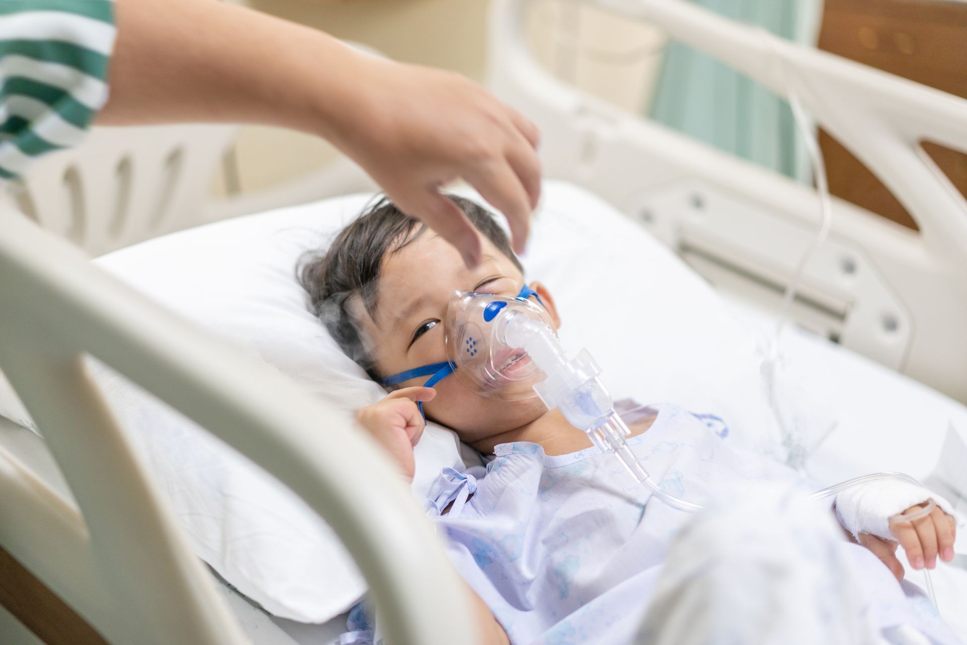 ein kleiner Junge liegt in einem Krankenhausbett und trägt eine Sauerstoffmaske