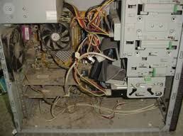 El interior de una carcasa de ordenador de sobremesa polvorienta y anticuada, con componentes internos expuestos y cables enredados.