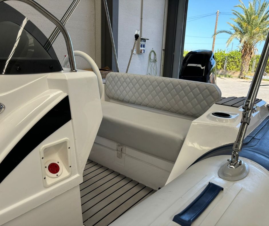 Interior de barco blanco con asientos tipo banco y volante, motor visible al fondo.