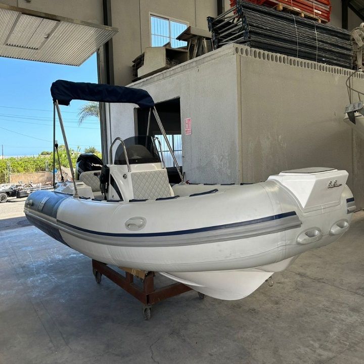 Embarcación inflable de color blanco con toldo azul, en un entorno de almacén.