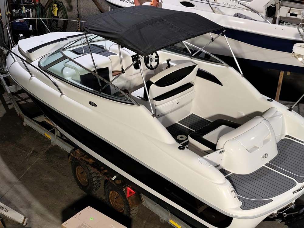 Lancha motora blanca con toldo negro amarrada en un astillero, vista desde arriba.