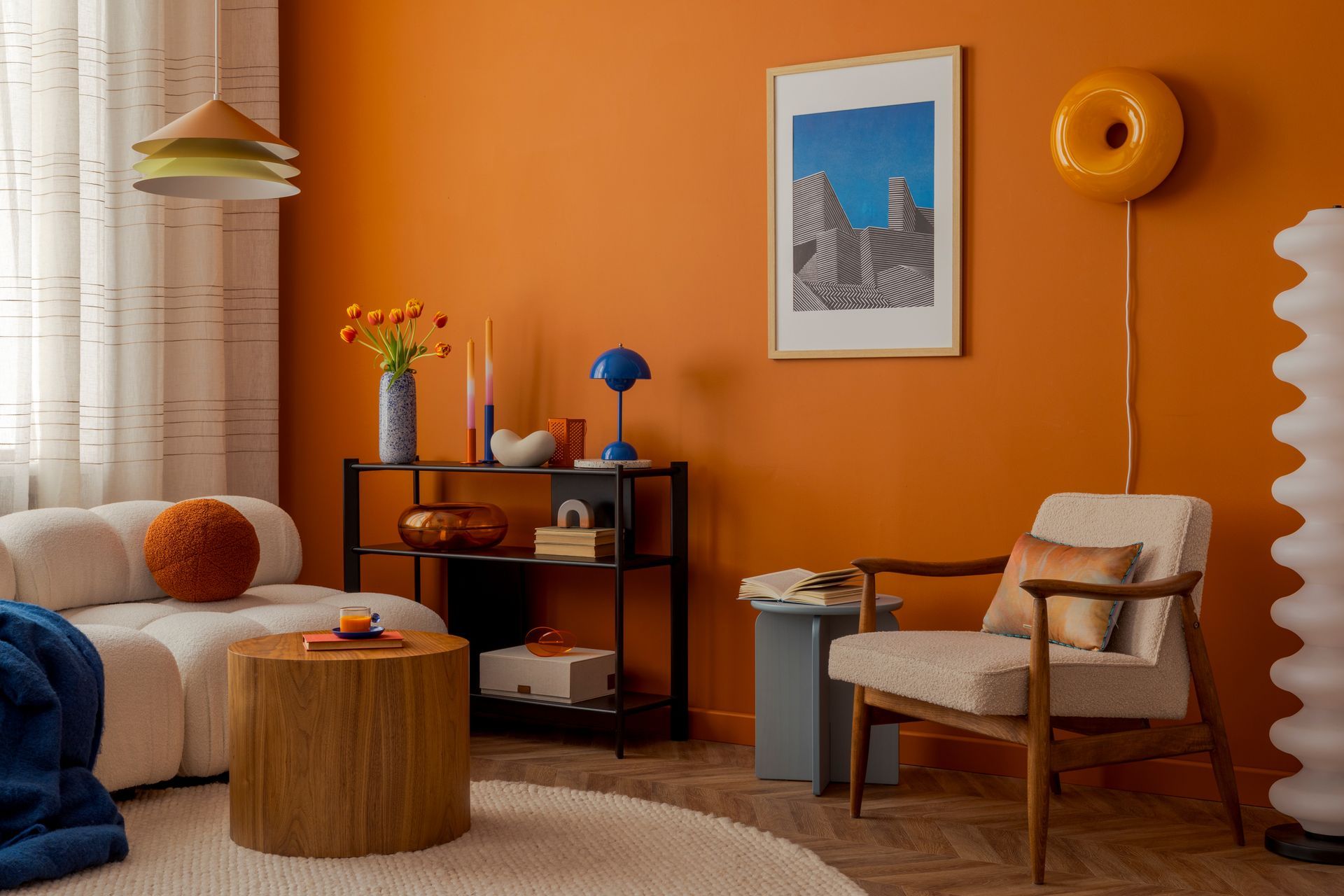 Salon orange cosy avec fauteuil, table ronde, lampe, tapis et tableau encadré.