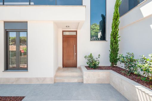 Entrée de maison moderne avec porte d'entrée en bois, marches et murs extérieurs blancs paysagés