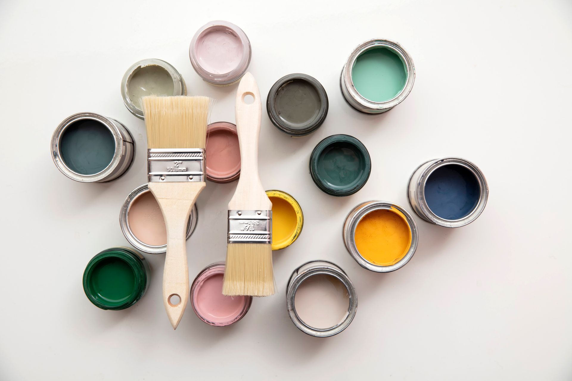 Pinceaux et pots de peinture ouverts disposés sur un fond clair