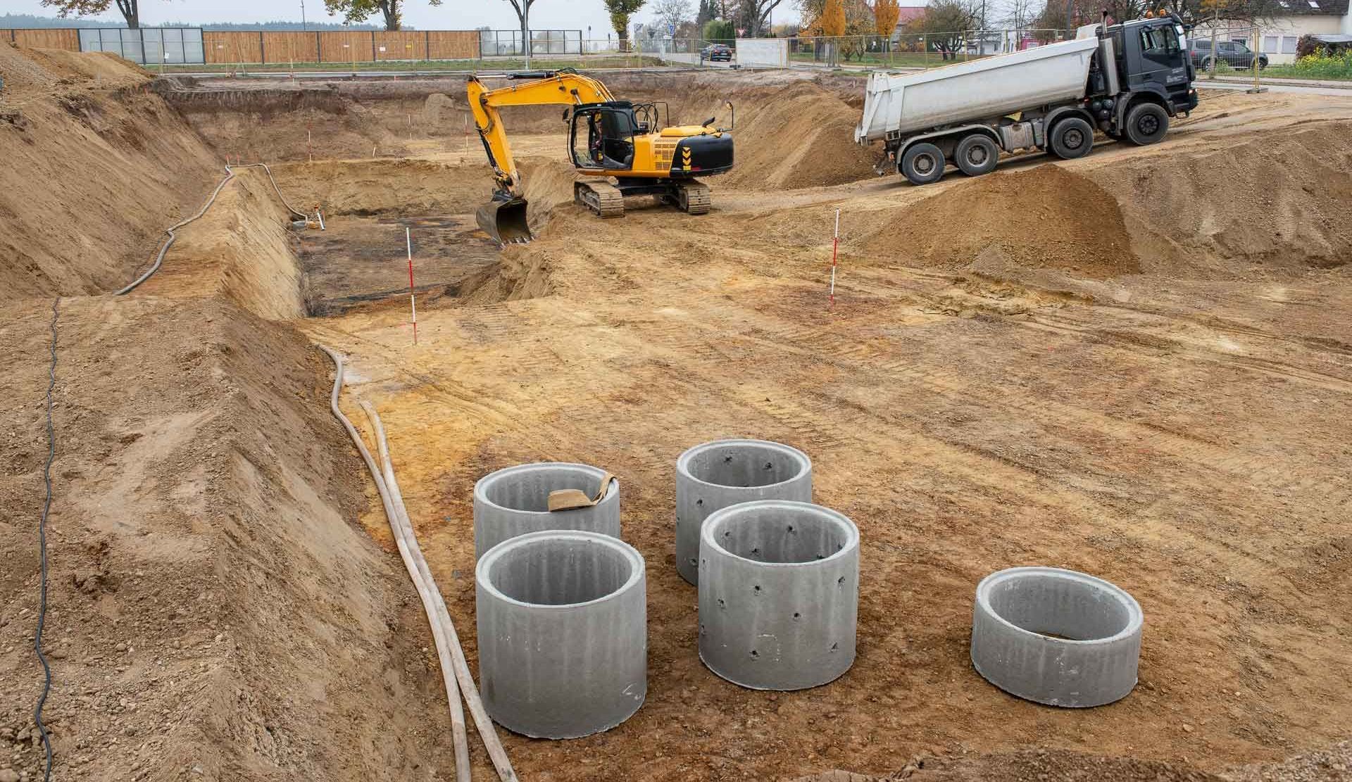 eine Baustelle mit Betonringen und einem Muldenkipper.