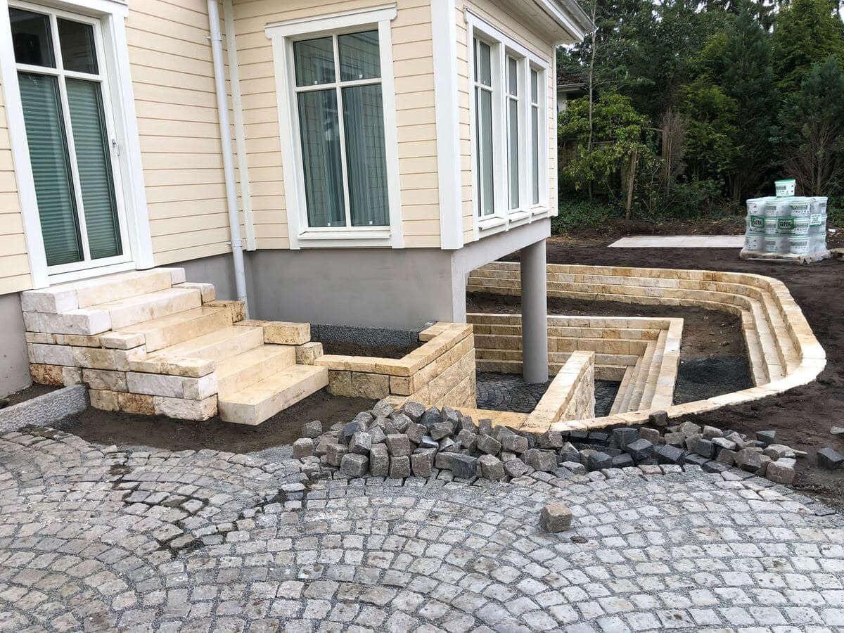 ein Haus mit Treppen und einem gemauerten Gehweg davor.