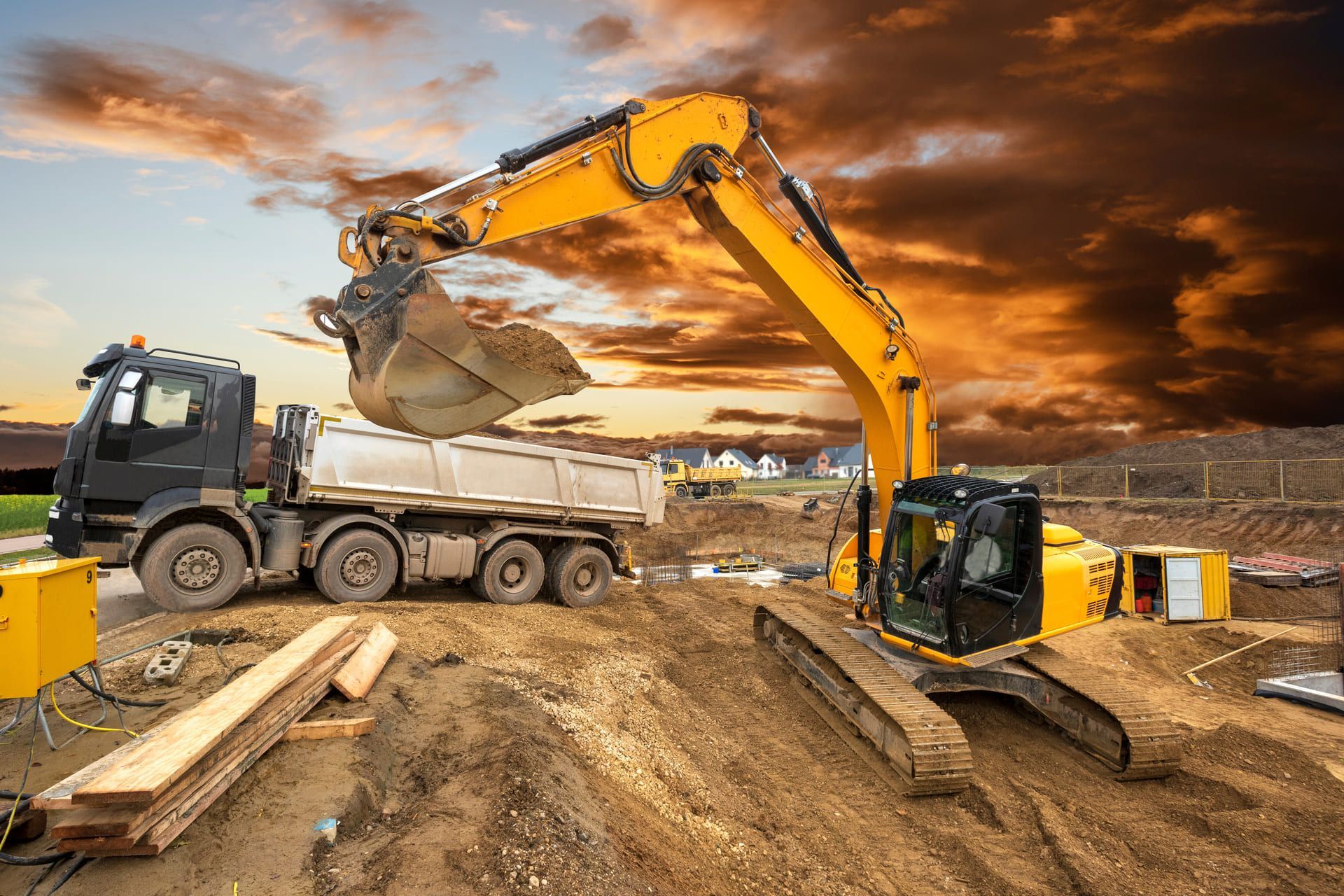 Ein Bagger belädt einen Muldenkipper auf einer Baustelle.