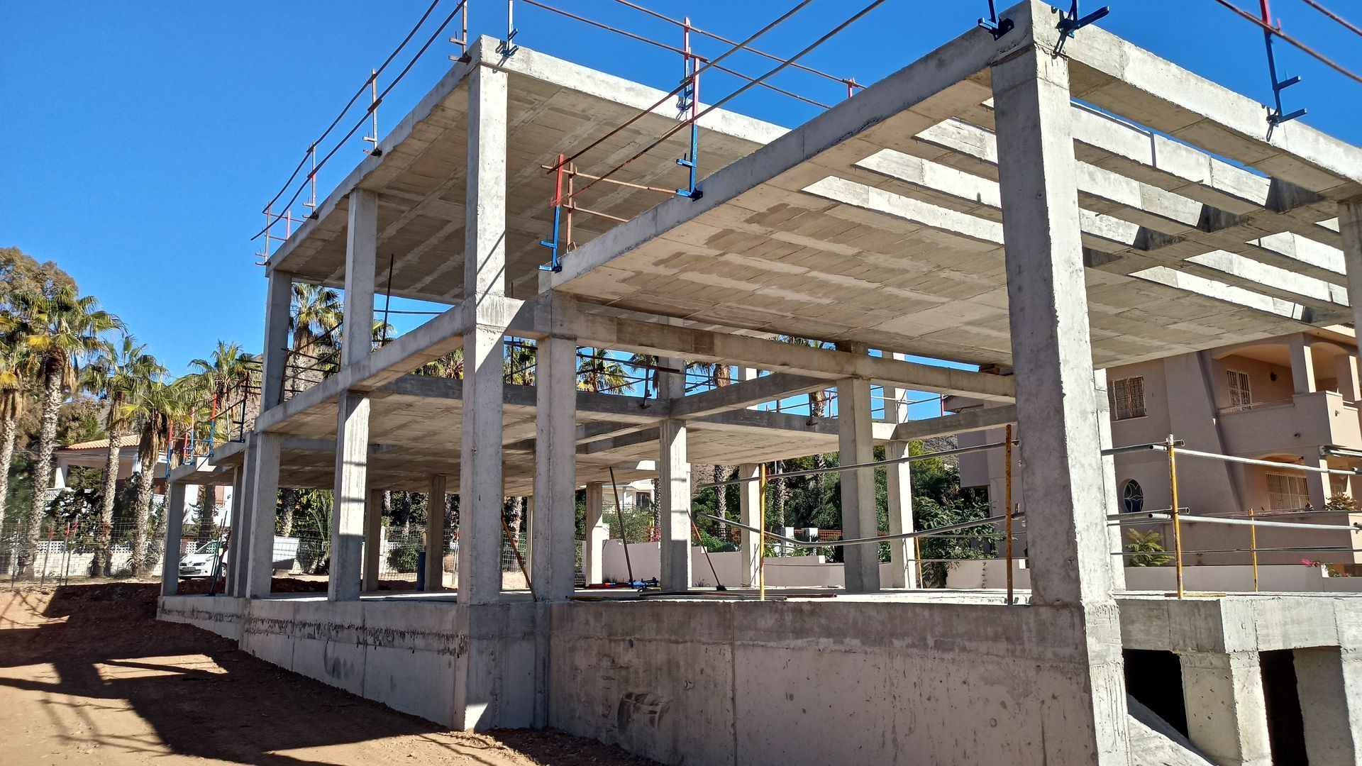Sitio de construcción de un edificio con andamios amarillos contra un cielo azul.