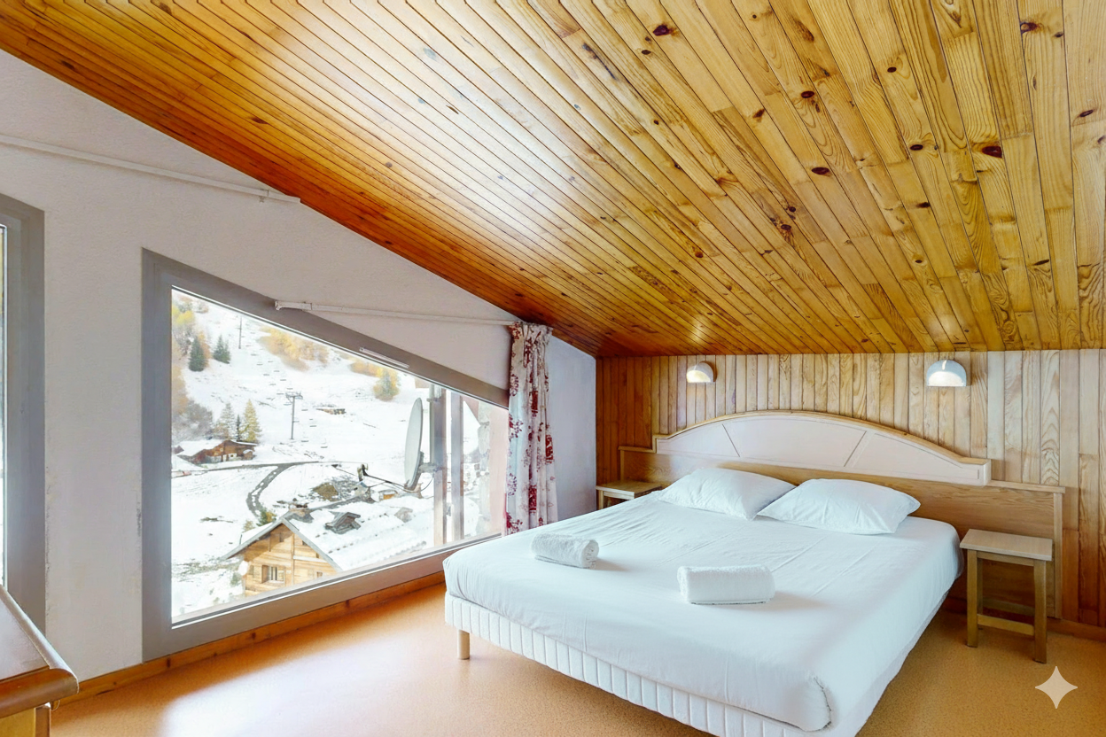 Bedroom with a bed, large window showing snow-covered mountains, and wood-paneled ceiling.