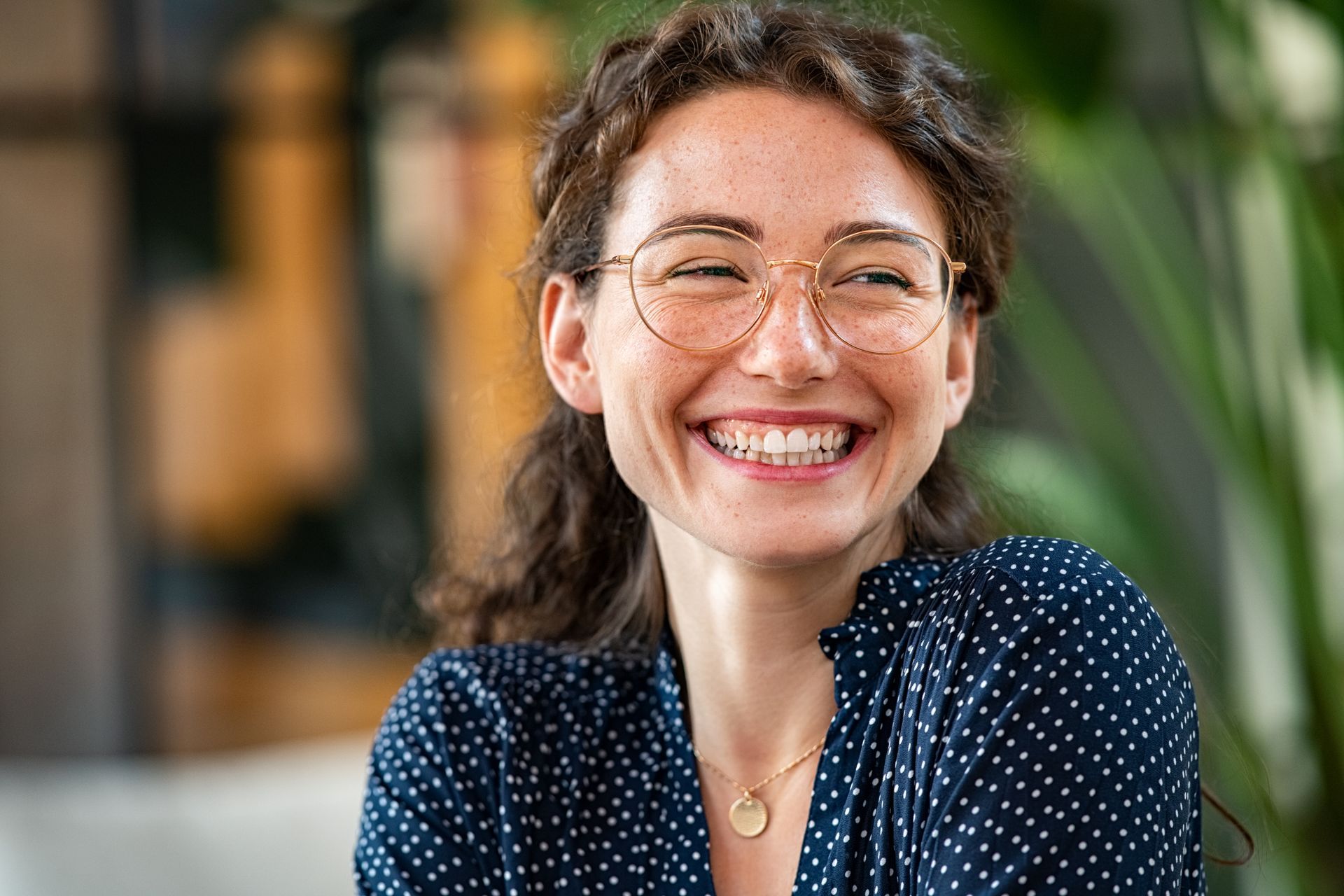 Une femme brune avec un chemisier bleu et des lunettes