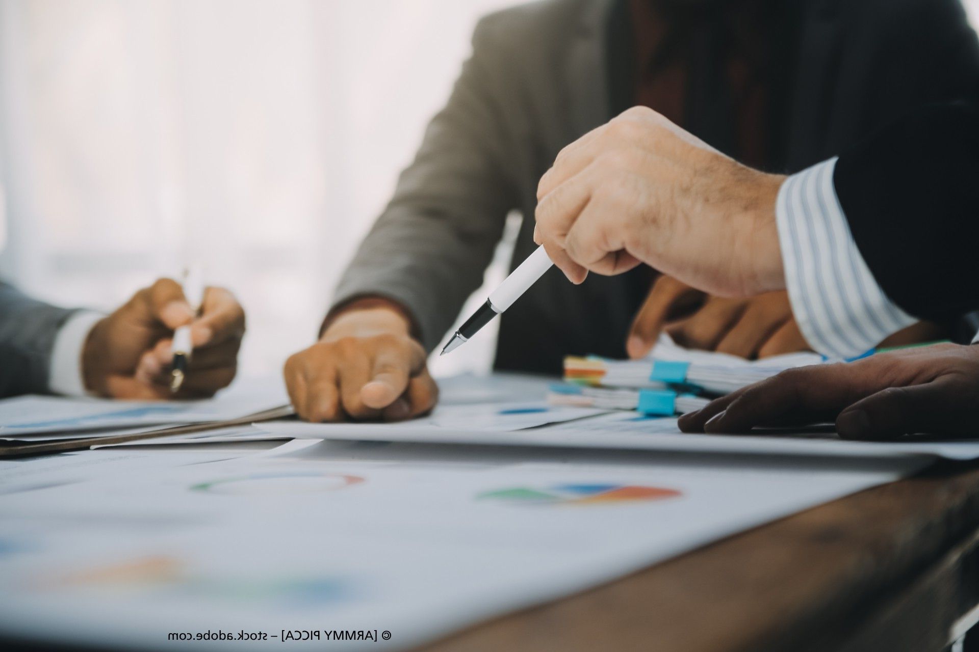 Klemmbrett, Taschenrechner, Dokumente, Laptop, Person mit Blazer und Hemd an Schreibtisch