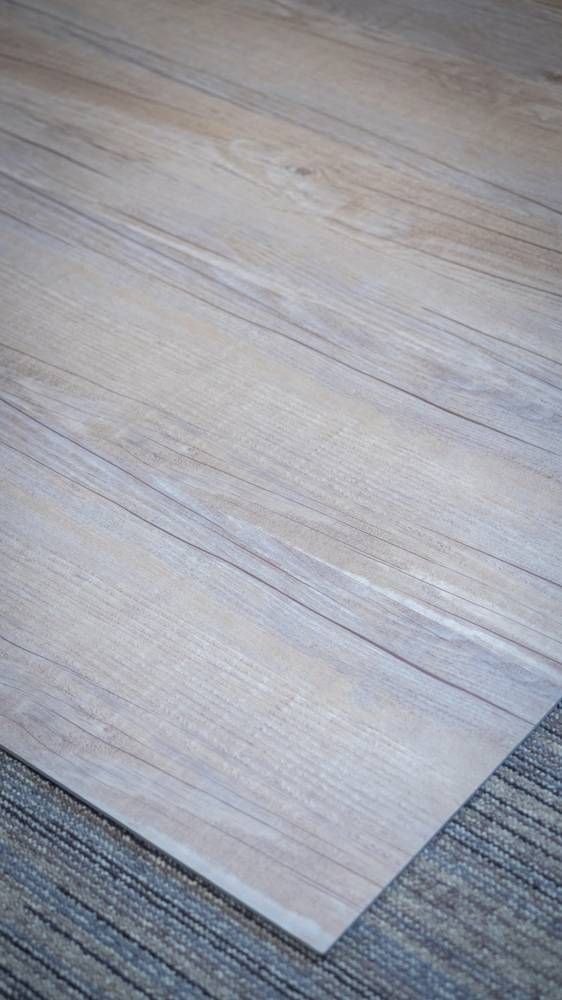 Parquet clair au veinage discret, avec le bord d’un tapis foncé dans le coin