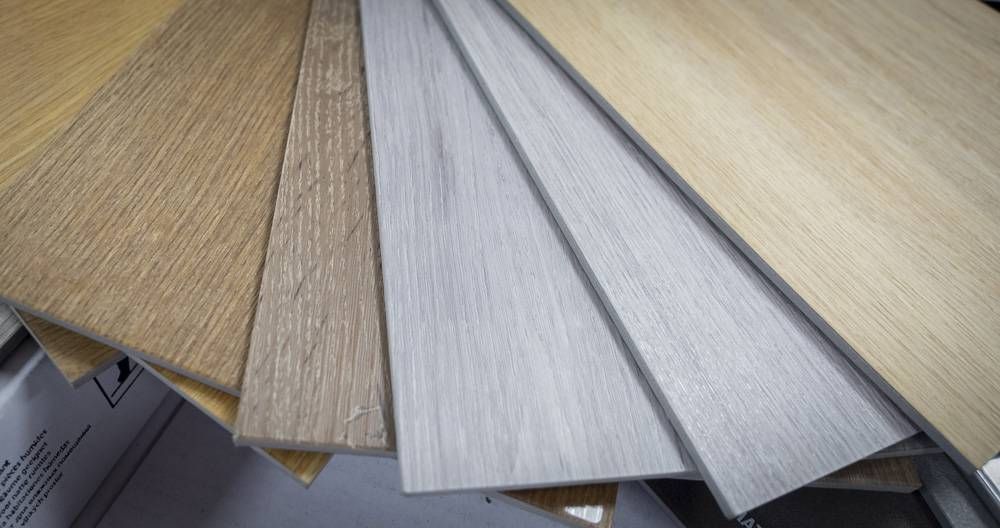 Échantillons de revêtement de sol stratifié imitation bois, disposés en éventail dans des tons beige, gris et argentés