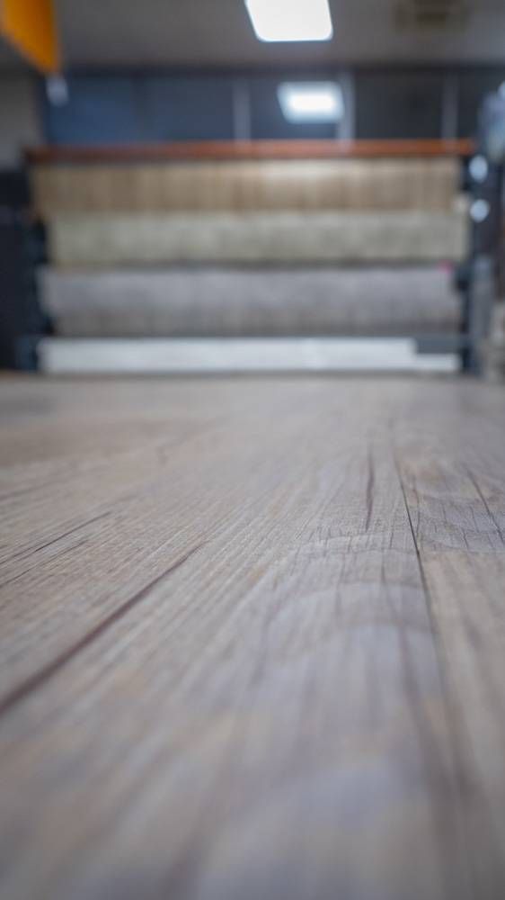 Vue en contre-plongée d’un parquet menant à un escalier flou, avec des murs bleus et une petite lumière au-dessus.