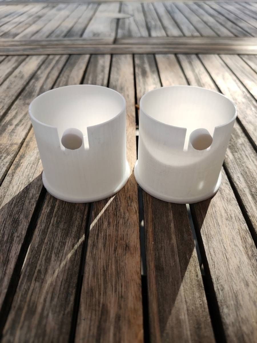 Deux gobelets blancs en plastique avec des becs verseurs latéraux, posés sur une terrasse en bois au soleil