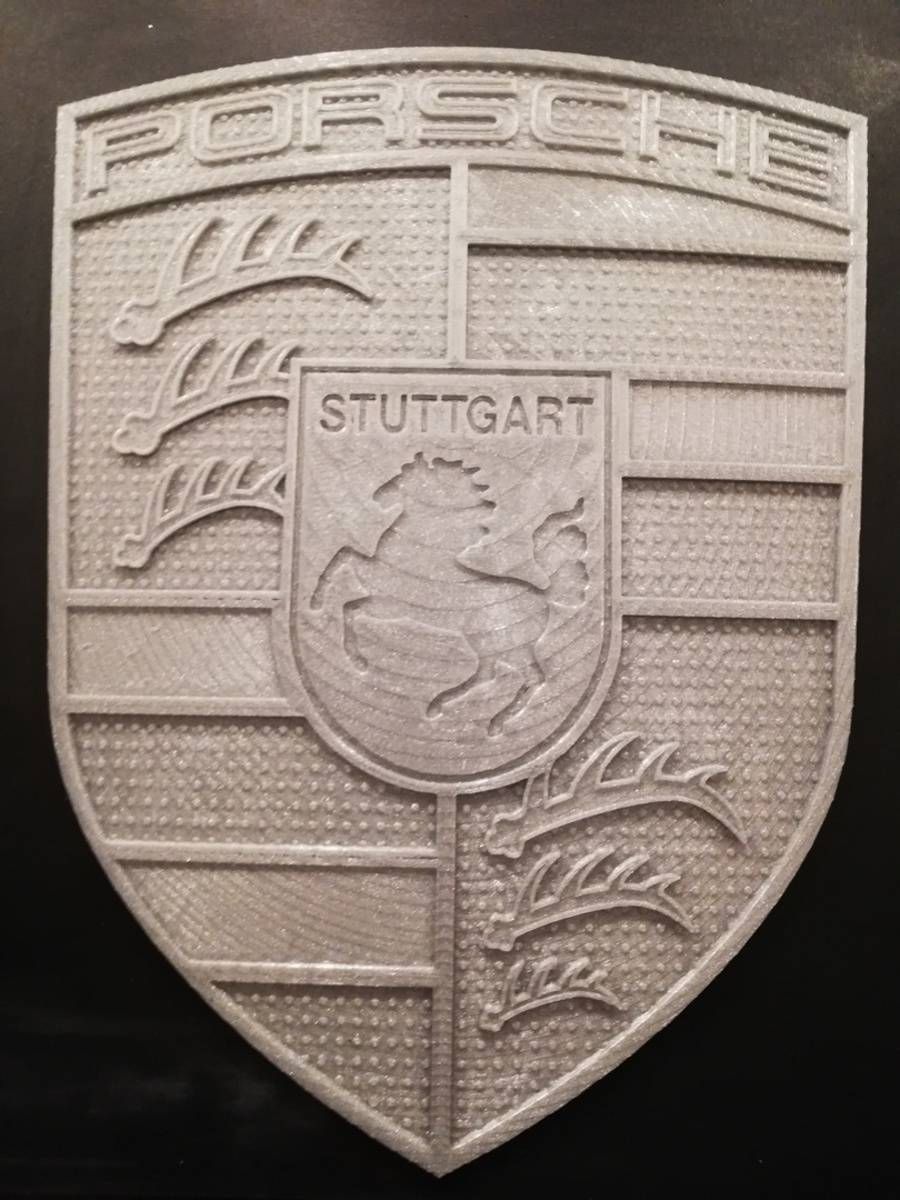 Emblème argenté du blason Porsche Stuttgart sur fond noir
