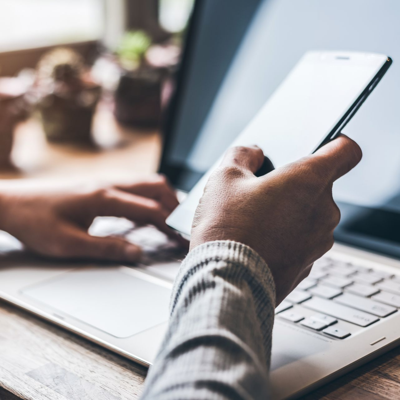 Une personne utilise simultanément un ordinateur portable et un smartphone à un bureau.