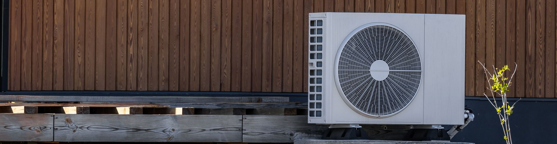Unité de climatisation blanche fixée à un mur en bois.