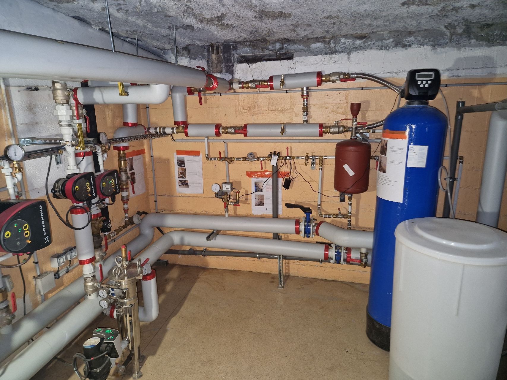 Local technique avec les tuyaux, les réservoirs, les pompes et les commandes du système de chauffage fixés au mur.