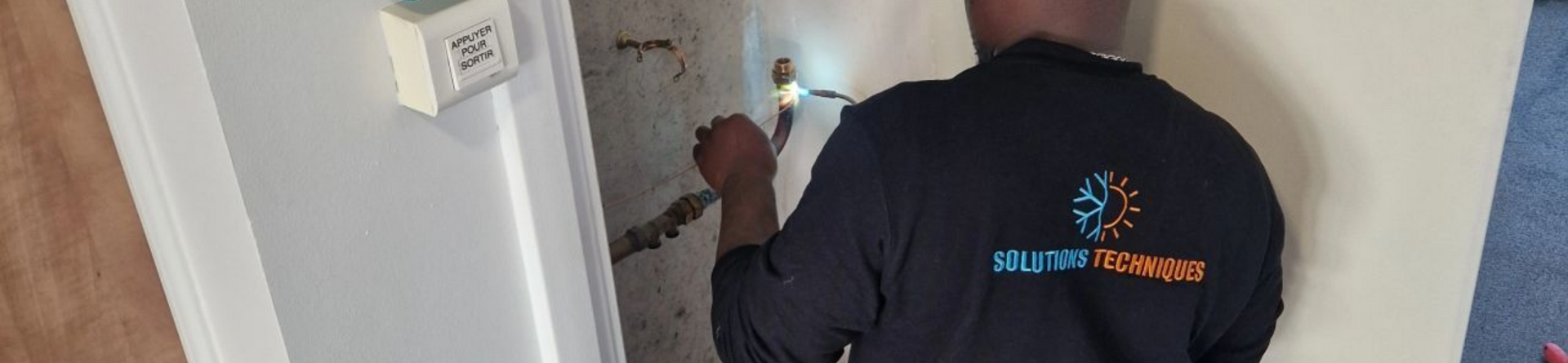 Une personne soude un tuyau à l'intérieur d'un bâtiment.