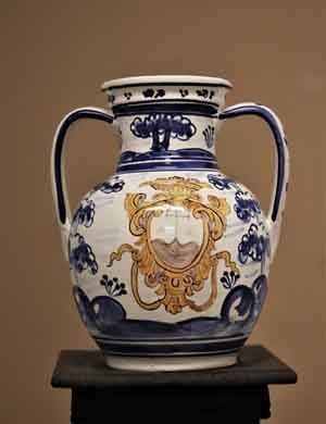 Un jarrón azul y blanco con un escudo de armas está sobre una mesa.