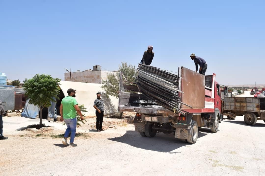 Ein Mann steht neben einem Lastwagen, der mit Stühlen beladen wird.