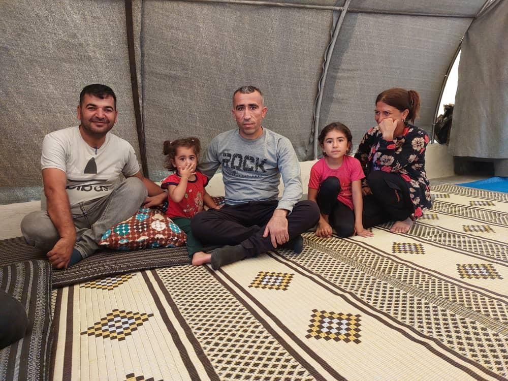 Eine Gruppe von Menschen sitzt auf einem Teppich in einem Zelt.