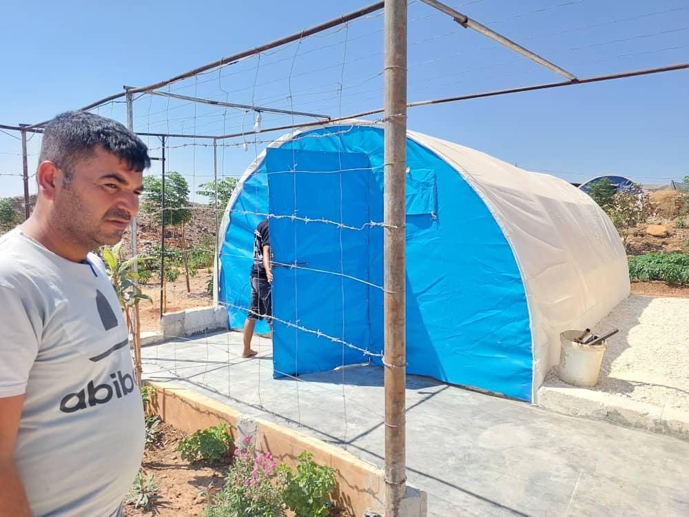 Ein Mann steht vor einem blau-weißen Zelt.