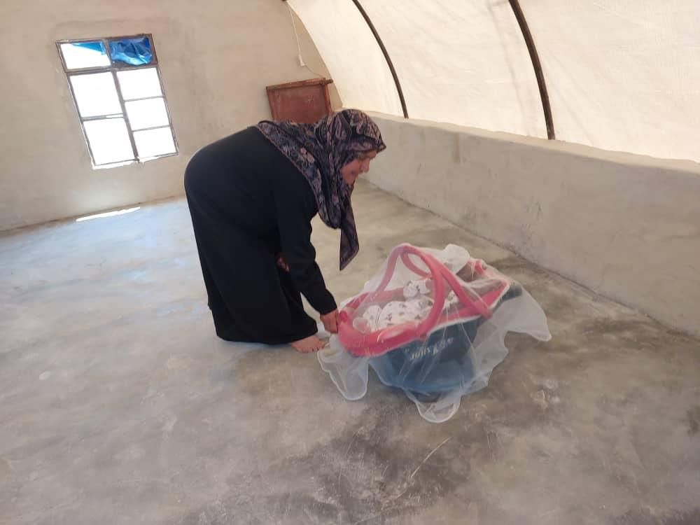 Eine Frau mit Kopftuch packt etwas in eine Plastiktüte