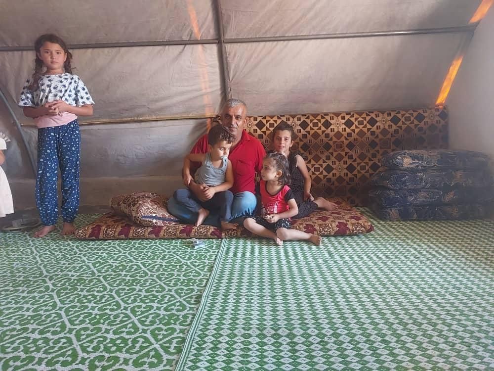 Ein Mann und drei Kinder sitzen auf einem Sofa in einem Zelt.