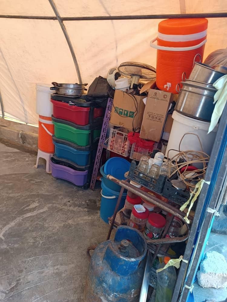 Unter einem Zelt sind eine Menge Eimer, Töpfe und Kisten übereinander gestapelt.