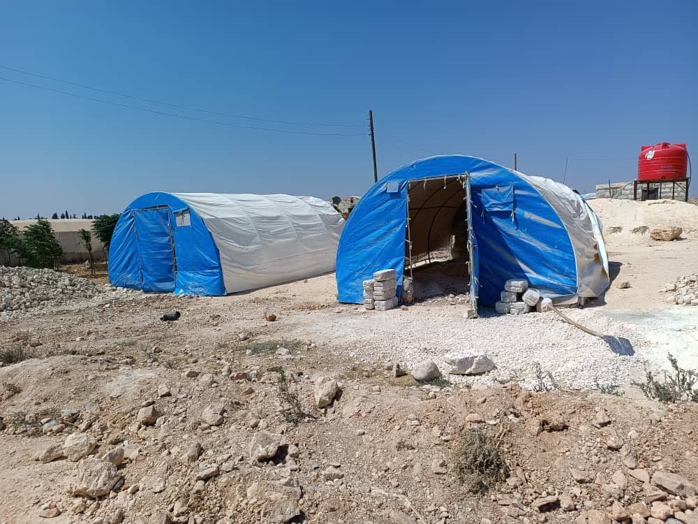 Zwei Zelte stehen mitten auf einem Feld.