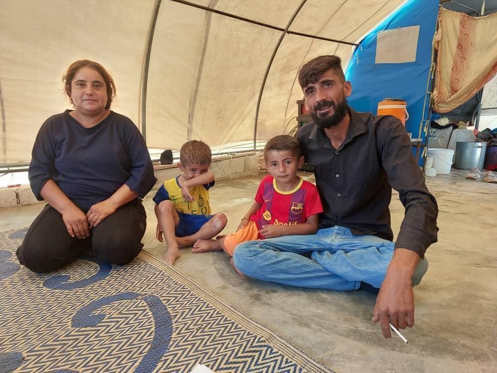 Eine Familie sitzt in einem Zelt auf dem Boden.